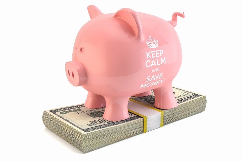 Cofre de porco com a escrita "Keep Calm and Save Money" na lateral. O cofre está em cima de notas de dólares